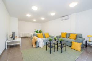 a living room with a blue couch and yellow pillows at Jouvacations Ripolles Figueres-Vilafant in Vilafant