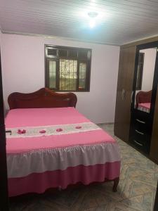 a bedroom with a pink bed and a mirror at Casa da Inês in Santa Teresa