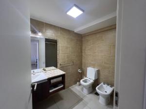 a bathroom with a toilet and a sink and a mirror at Domus piso 2 in Necochea +4 photos