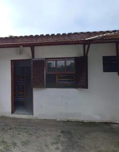 a white house with two windows and a door at Quarto compartilhado in Bertioga