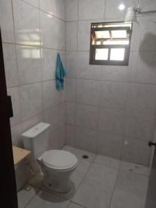 a bathroom with a white toilet and a window at Quarto compartilhado in Bertioga