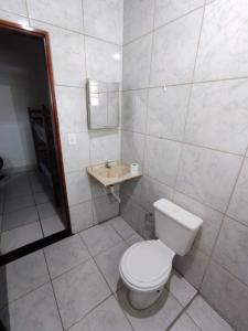 a bathroom with a white toilet and a sink at Quarto compartilhado in Bertioga +2 photos