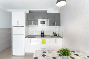 a kitchen with white cabinets and a white refrigerator at El Nido de los Ángeles in Playa del Ingles
