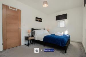 a bedroom with a bed and a wooden door at 2 Bedroom House By AR Properties Short Lets & Serviced Accommodation Colchester with Garden in Colchester