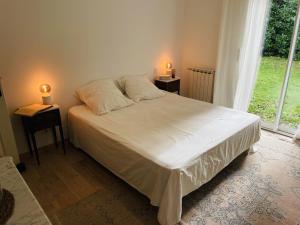 ein Schlafzimmer mit einem weißen Bett und zwei Nachttischen in der Unterkunft Villa Casalera - piscine, spacieuse & familiale in Dax + 29 Fotos