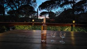 a bottle of wine sitting on a wooden table with two wine glasses at Mobil-Home à louer dans le golfe de Saint-Tropez in Gassin