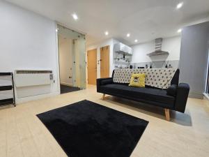 a living room with a black couch and a kitchen at Bee Accommodations - NG1 Apartment in Nottingham