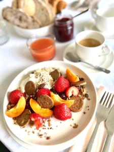 een bord met aardbeien en sinaasappels en een kopje koffie bij B&B near Ghent in Merelbeke