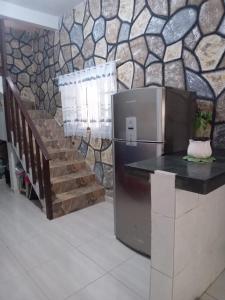 a kitchen with a refrigerator and a stone wall at casa da mata in Ubatuba
