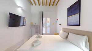 Un dormitorio blanco con una cama grande y un televisor de pantalla plana. en MyFlats Luxury City Center, en Alicante