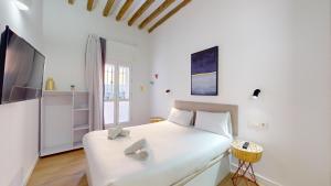 Un dormitorio blanco con una cama grande y un televisor. en MyFlats Luxury City Center, en Alicante