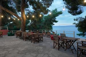 un patio con tavoli, sedie e un albero di Scala Village Camping a Vatopedi
