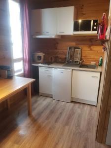 a kitchen with white cabinets and a wooden floor at Superbe Studio Ambiance Chalet in Ustou