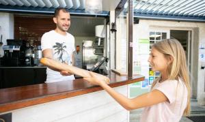 Una ragazza tiene una pagnotta di pane al bancone di Camping 4 étoiles - Piscine - eeihec a Loupiac