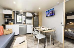 una cucina e un soggiorno con tavolo e sedie di Camping 4 étoiles - Piscine - eeihec a Loupiac