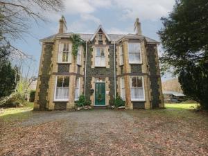 an old brick house with a green door at Plas Dorothea in Caernarfon