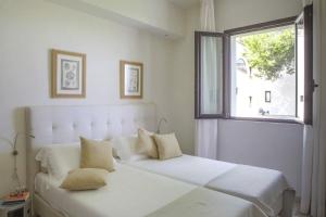 Una cama blanca en una habitación con ventana. en Masseria Ceratonia by Raro Villas, en Baia Verde