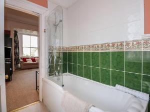 a bathroom with a white tub and green tiles at Plas Dorothea in Caernarfon +26 photos