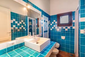 bagno piastrellato blu con lavandino e servizi igienici di Le Case di Mara - Appartamento Vista Mare a Porto Rotondo a Porto Rotondo