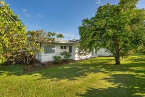 a white house with a tree in the yard at Hihimanu House in Princeville