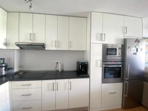 Una cocina con gabinetes blancos y un refrigerador de acero inoxidable. en Casa Valdes Los Cristianos Center, en Los Cristianos 8 fotos más