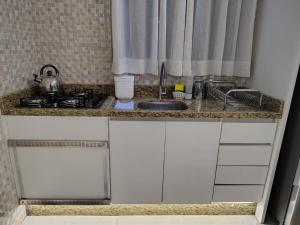 a kitchen counter with a sink and a stove at B&B Conforto próximo ao Aeroporto in São José dos Pinhais +18 photos