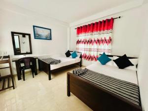 a room with two beds and a chair in it at Moonstone Holiday Cottages in Badulla