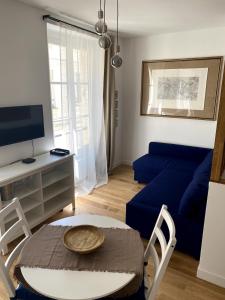 a living room with a blue couch and a table at La Petite Paroisse Classé 3 étoiles Elégant & Proche Marché in Versailles