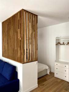 a bedroom with a blue couch and a wooden wall at La Petite Paroisse Classé 3 étoiles Elégant & Proche Marché in Versailles
