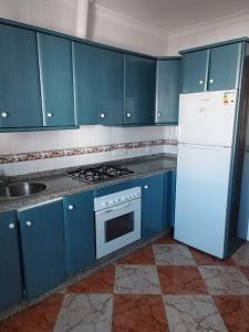 a kitchen with blue cabinets and a white refrigerator at Casamanuela in Aracena