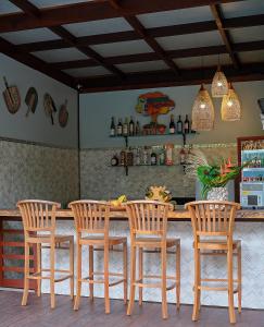 a kitchen with a bar with four wooden chairs at Encantes do Nordeste in Barreirinhas