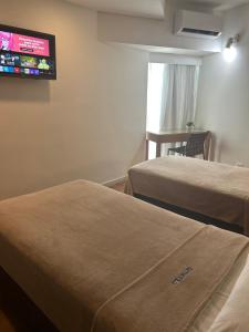 ein Hotelzimmer mit zwei Betten und einem Flachbildfernseher in der Unterkunft Hotel Barramares in Recife