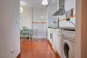 een keuken met een wasmachine en een tafel met stoelen bij FGDR342E La Playona in San Vicente de la Barquera
