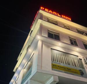 a white building with a neon sign on top of it at Hotel Pearl inn in Rudrapur