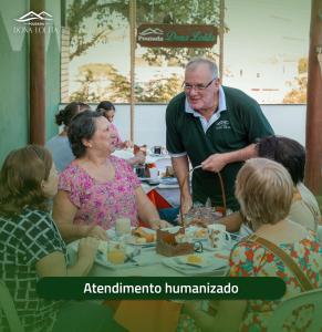 a man standing at a table with a group of people at Pousada Dona Lolita in Cachoeira Paulista