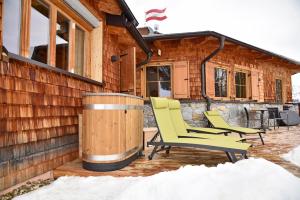 two chairs and a barrel on a deck in front of a cabin at Bockspitze Deluxe Appartements in Hinterweisspriach