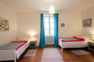 - 2 lits dans une chambre avec des rideaux bleus et une fenêtre dans l'établissement L' ostal de maite, à Annesse-et-Beaulieu
