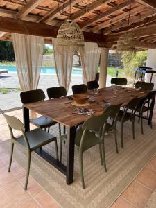 einen langen Holztisch und Stühle unter einer Holzdecke in der Unterkunft Villa Casalera - piscine, spacieuse & familiale in Dax