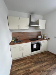 una cucina con mobili bianchi e un lavandino di Ferienwohnung am Liebesgrund a Lüneburg