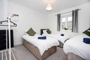 Cette chambre comprend 3 lits dans une chambre dotée de murs blancs et d'une fenêtre. dans l'établissement Doulton House - 2 Bedroom Sleeps 5 Wifi Parking, à Wharton