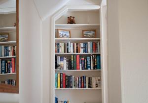 a book shelf filled with lots of books at Stone Hall Mill Cottage - Tranquil Countryside Haven in Pembrokeshire in Saint Lawrence