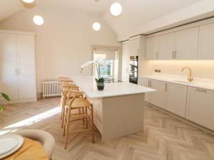 a kitchen with white cabinets and a table with chairs at Chatsworth Suite in Buxton +40 photos