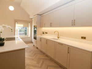 a kitchen with white cabinets and a sink at Chatsworth Suite in Buxton