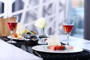 zwei Teller Essen und zwei Gläser Wein auf einem Tisch in der Unterkunft Hotel Porto in Radomsko