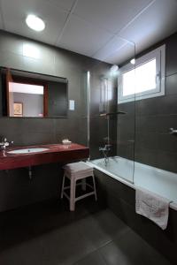 a bathroom with a tub and a sink and a stool at Hotel Marblau Tossa in Tossa de Mar