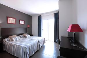 a bedroom with a bed with a red lamp and a window at Hotel Marblau Tossa in Tossa de Mar