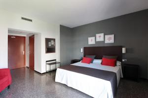 a bedroom with a large bed and a red chair at Hotel Marblau Tossa in Tossa de Mar