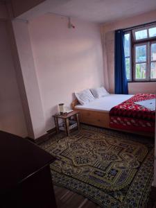 拉瓦格拉Hotel Rainbow Regency Ravangla South Sikkim的一间卧室，里面有一张床、一张桌子和一扇窗户