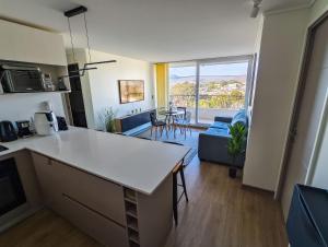 a kitchen and living room with a large window at Hermoso y nuevo departamento con gran vista - Papudo in Papudo