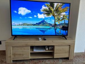 a flat screen tv sitting on top of a wooden entertainment center at Cal SalMaré seafront apartment with rooftop terrace and pool in Calafell